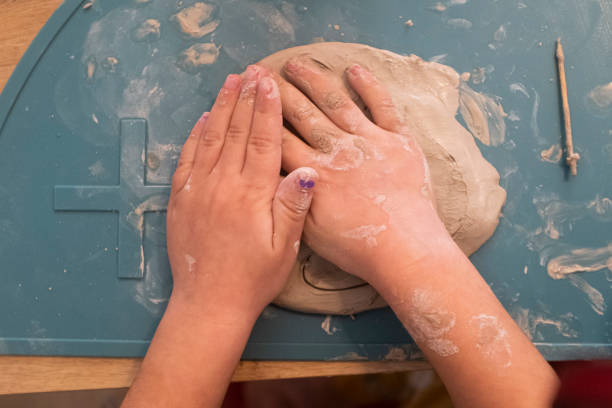 istock Dirty kid hands playing with clay on a blue table close up still 1465459039