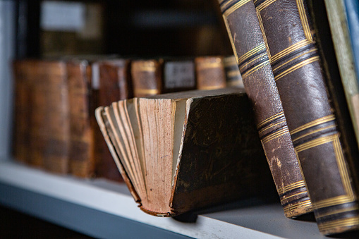 Very old books sitting on the shelves in the library. Books as a symbol of knowledge.