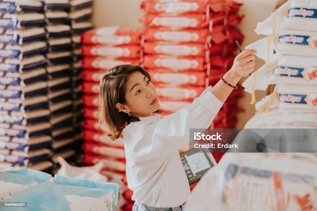 Checking quality of rice sack before delivery to customer Wholesale Thai rice owner at her rice shop for working everyday Supply Chain Stock Photo