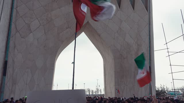 People holding the Iranian flag and placards under the Azadi Tower