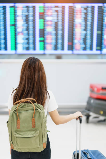 istock Young woman with backpack looking at the flight time information board in international airport, before check in. Travel, Vacation, trip and Transport concept 1465466690