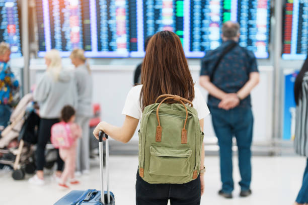 istock Young woman with backpack looking at the flight time information board in international airport, before check in. Travel, Vacation, trip and Transport concept 1465466691