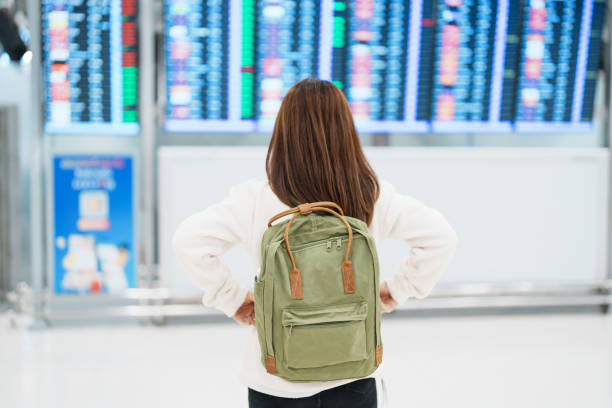 istock Young woman with backpack looking at the flight time information board in international airport, before check in. Travel, Vacation, trip and Transport concept 1465466697