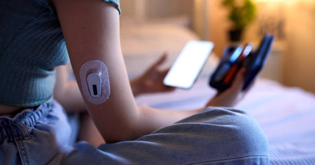 Zbliżenie na cukrzycę dziewczyny siedzącej na łóżku w domu sprawdzającej poziom insuliny w aplikacji na telefon komórkowy – zdjęcie