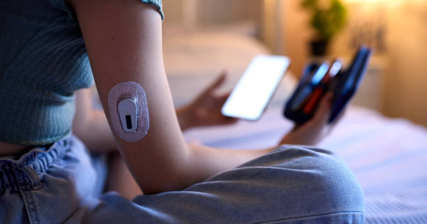 close up of diabetic girl sitting on bed at home checking insulin levels on mobile phone app - insulin imagens e fotografias de stock