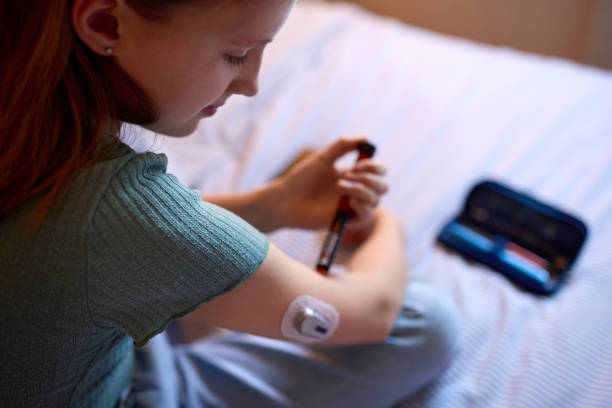 primer plano de una niña diabética en la cama en casa usando la pluma de insulina para medir el nivel de azúcar en la sangre - diabetes home interior blood sugar test healthcare and medicine fotografías e imágenes de stock