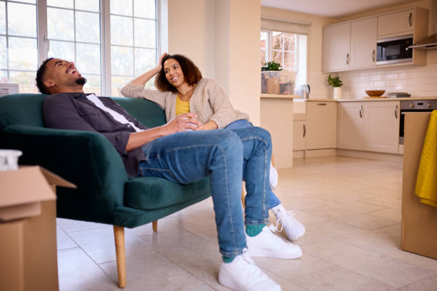 istock Couple Taking A Break From Unpacking Boxes Sitting On Sofa Looking Around New Home On Moving Day 1465479446