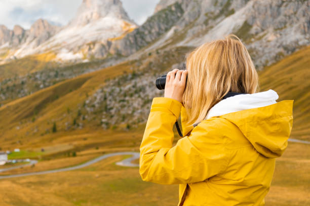istock Woman traveling exploring the mountains views covered by clouds looking through binoculars 1465479502