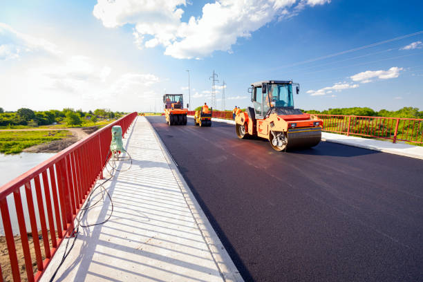 Hot asphalt is spreading with steamroller during road works Zrenjanin, Vojvodina, Serbia - June 8, 2021: View on several steamrollers that are flatting fresh asphalt, spreading layer of hot tarmac on prepared ground at the bridge under construction. pavement ends sign stock pictures, royalty-free photos & images