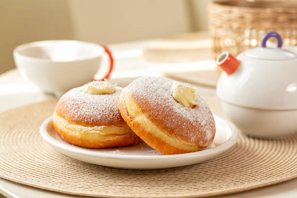 istock Breakfast table with Krapfen or berliner, or doughnut, or bombolone with cream filling. Tea cup and tea pot. 1465483336