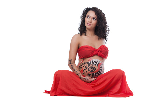Pregnant caucasian woman with beautiful curly hair, sitting and leaning on her hands with a smily cute attitude.