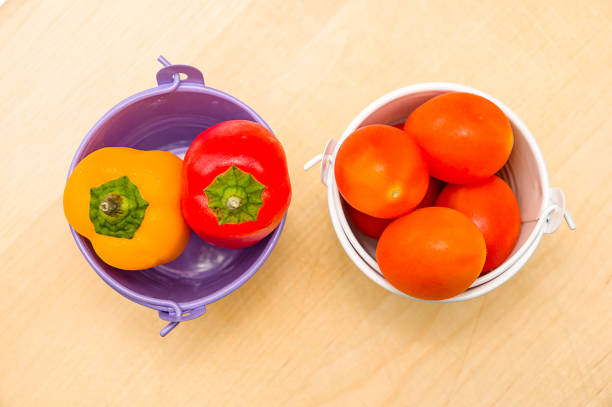 The fresh tomatoes and peppers on a wooden table in a kitchen