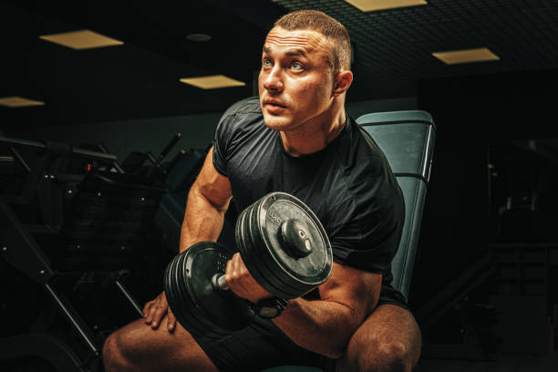 istock Muscular young man lifting weights in a dark gym 1465486214