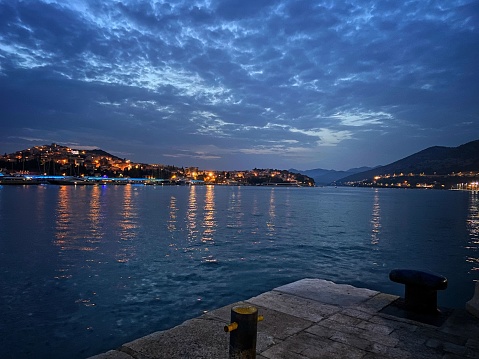 A beautiful view of the blue sea reflecting the city lights of Dubrovnik at dusk in Croatia