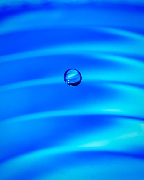 istock Vertical close-up shot of a droplet dropping on a blue water surface 1465488593