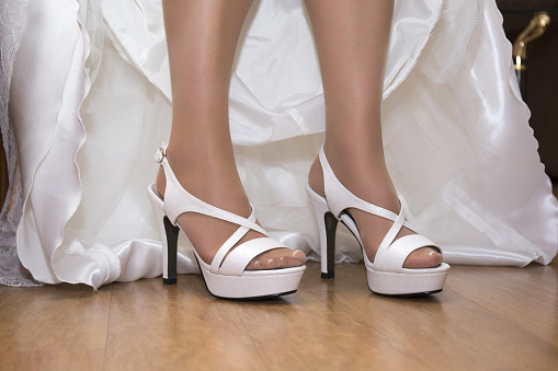 A closeup shot of a bride wearing white shoes