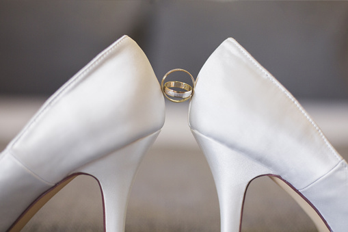 A selective focus of white bridal shoes with wedding rings