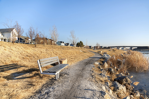 A coastal bench on background of buildings overlooking the lake