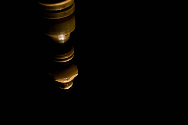 An upside-down reflection of a wooden queen chess piece on black background