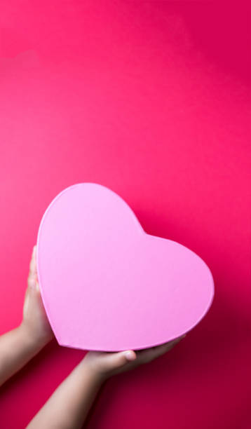 istock Hands holding a heart-shaped gift isolated on a red background with free space for text 1465492433