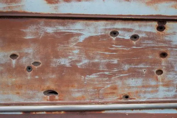 An old abandoned Ford Courier Sedan Delivery, rusty and with bullet holes