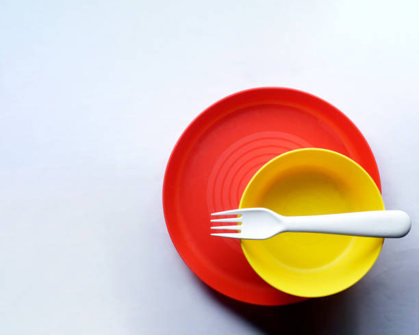 istock Top view of a red plate, a yellow bowl and a white fork on a white surface with copy space 1465493540