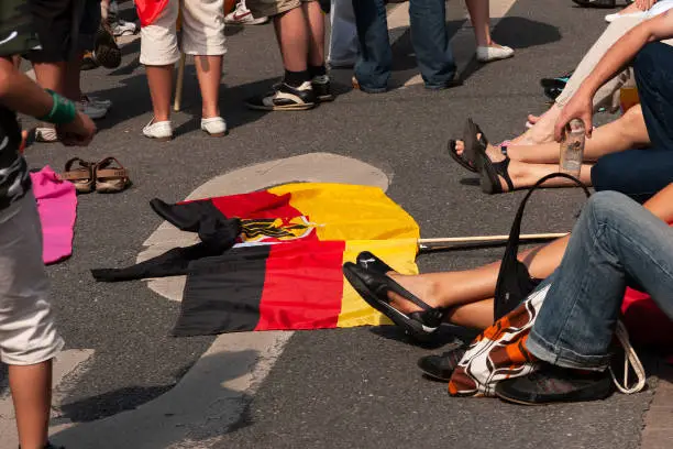 Public viewing: The Germany flag with the federal eagle lies on the street in the midst of the visitors' feet.