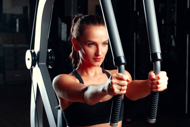 istock Young attractive woman doing exercises for arms in a training machine 1465494689