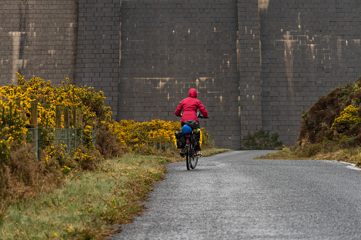 A close-up shot of a cyclist woman riding on the road at Ben Crom Reservoir, North Ireland