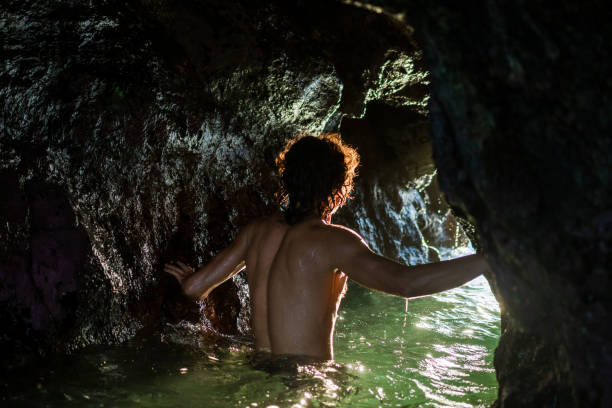 istock Young male relaxing along inside a cave in the water 1465497403
