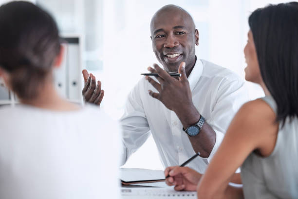 istock Meeting, discussion and team working on a project together in a modern office conference room. Teamwork, collaboration and professional black man talking to his colleagues in the workplace boardroom. 1465497802