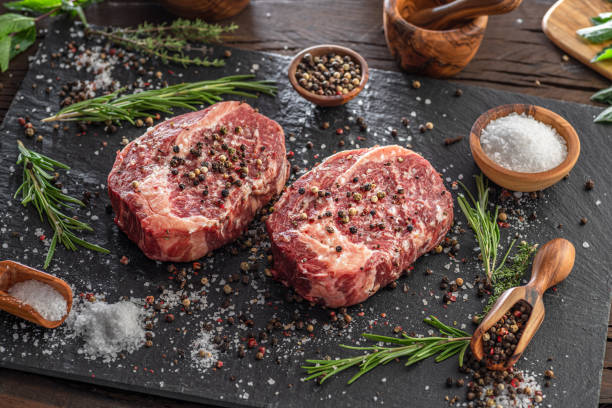 istock Raw Ribeye steaks with salt and herbs on grey board. Top view. 1465500147