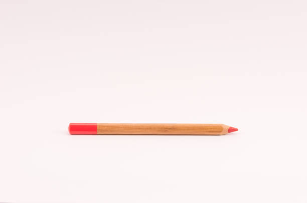 istock Closeup of a wooden red pencil on light opink empty surface 1465501092