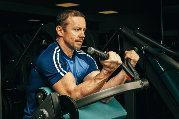 istock Senior man doing exercises for arms in a training machine in gym 1465502773