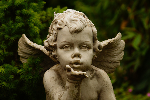 The sculpture of an angel breathes the kiss goodbye on a grave. Probably a series production. Signs of weathering.