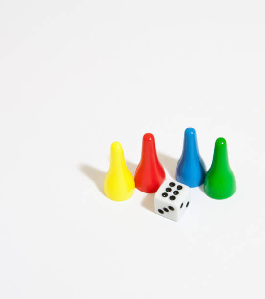 Plastic board game figures and a dice isolated on a white background