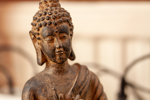 A closeup shot of a small figurine of Budda on a blurred background