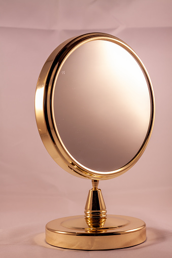 A golden mirror isolated on a pink background