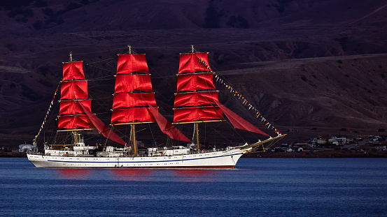 Sailing three-masted frigate with red sails. scarlet sails.