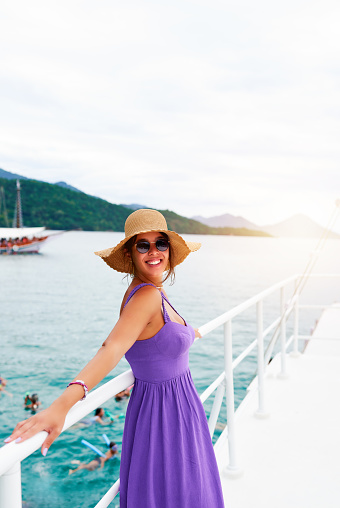 waist up portrait posing young brazilian woman with hat and dress smiling happy on a boat on a tourist trip in Brazil