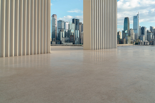 A shot of an empty concrete ground floor with a modern cityscape.