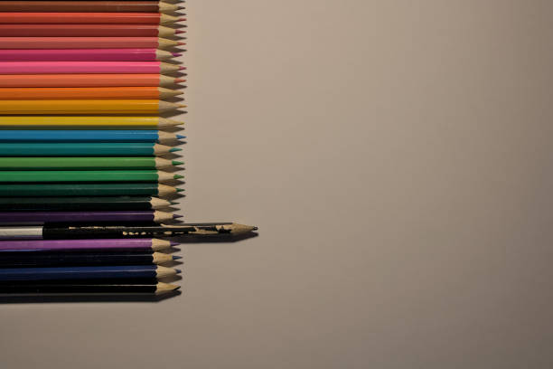 concept of individuality, new and clean coloured pencils and a black pencil, used, in prominence