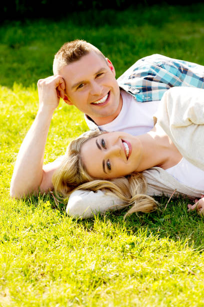 istock Romantic Caucasian couple lying in green grass 1465511690