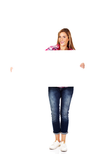 A young blonde woman wearing a checkered shirt and jeans and holding a white blank poster