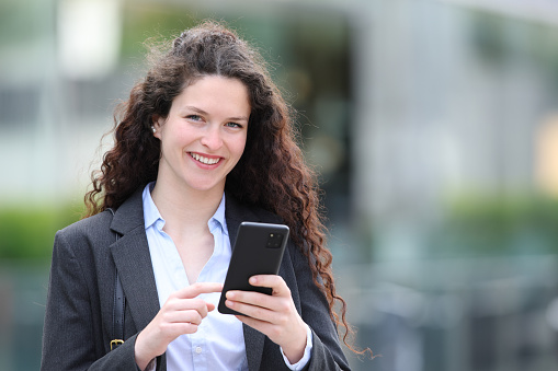 Businesswoman looking at you holding smartphone