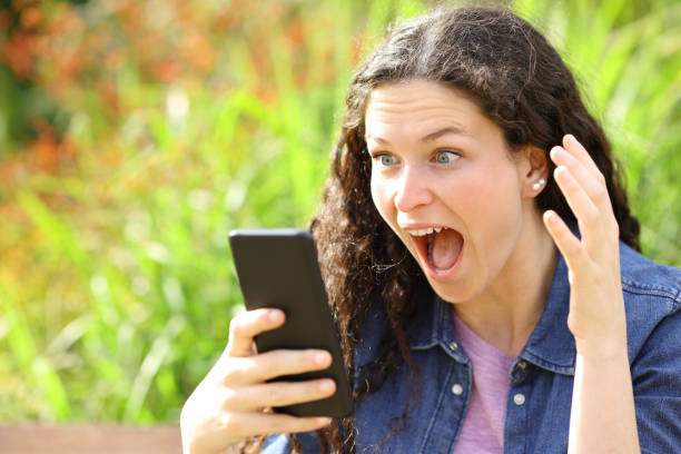 istock Amazed woman checking phone in a park 1465512486