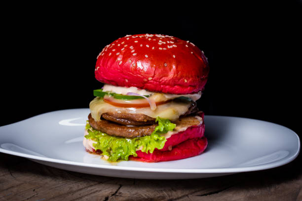 istock Delicious red cheeseburger on a white plate on a tree trunk on a black background 1465513441