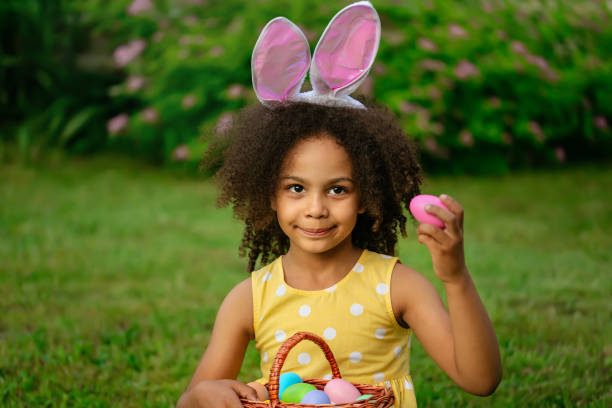 istock Little Black girl wtfring bunny ears gathering Easter eggs 1465518784