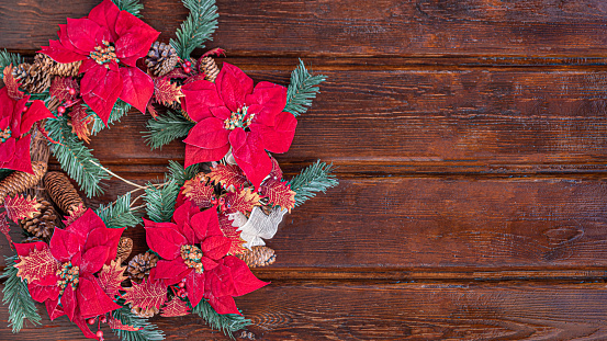 A top view of a Christmas wreath with poinsettia flowers isolated on a wooden background
