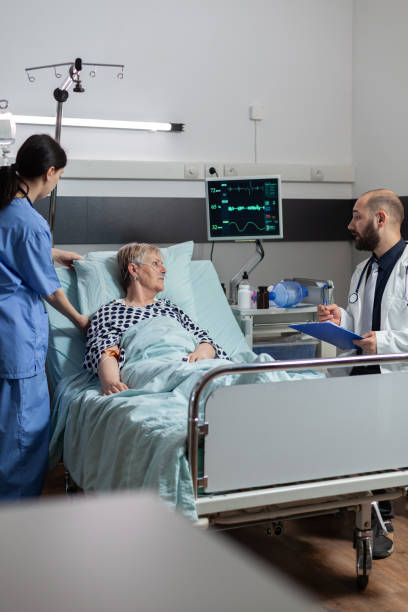 istock Doctor talking with elderly patient sitting next to bed 1465522047
